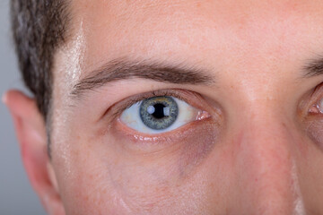 Obraz premium Close up of blue eye of caucasian businessman, isolated on grey background