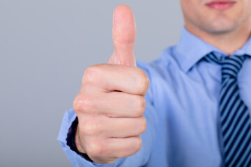 Midsection of caucasian businessman with thumb up, isolated on grey background