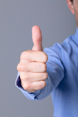 Midsection of caucasian businessman with thumb up, isolated on grey background
