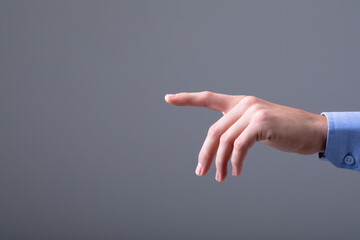 Midsection of caucasian businessman pointing with his finger, isolated on grey background
