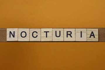 gray word nocturia made of wooden square letters on brown background