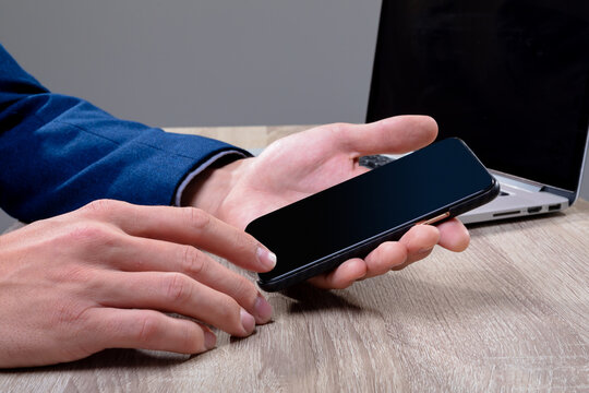 Midsection of caucasian businessman using smartphone and laptop, isolated on grey background