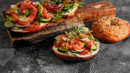 Food banner sandwich salad New York bagel with cream cheese, lettuce, cucumber, capers, onions and salted red fish. Excellent delicious breakfast or snack on cutting board. Copy space