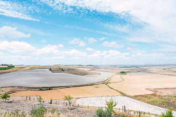 Rural landscape with different agricultural fields of ochre colors with a blue sky with clouds....