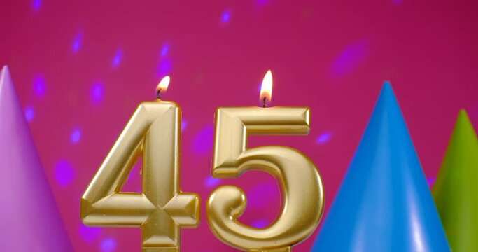 Burning birthday cake candle number 45. Happy Birthday background anniversary celebration concept. Birthday hat in the background