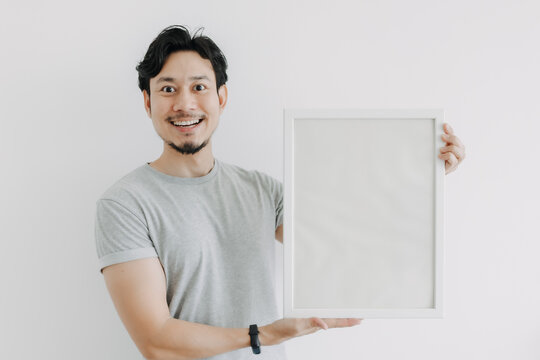 Happy Asian man holding an empty photo frame isolated on white background.