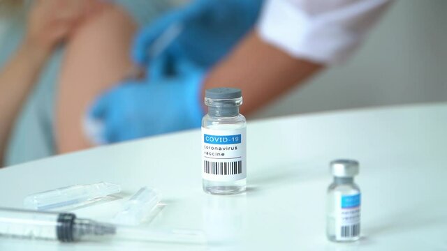 Ampula with vaccine covid-19 on background of nurses hands in gloves vaccinated patient. Nurse injects drug into hand from syringe. Coronavirus vaccination