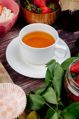 side view of a cup of tea with fresh ripe strawberries on rustic background