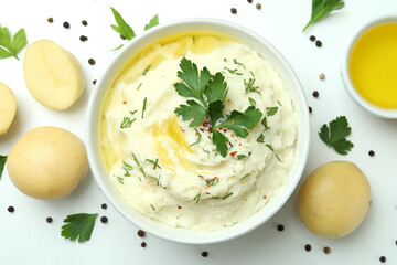 Plate of mashed potatoes and ingredients on white background