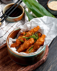 side view of chicken nuggets with herbs in a bowl on plaid tablecloth