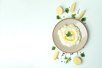 Plate of mashed potatoes and ingredients on white background