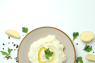Plate of mashed potatoes and ingredients on white background