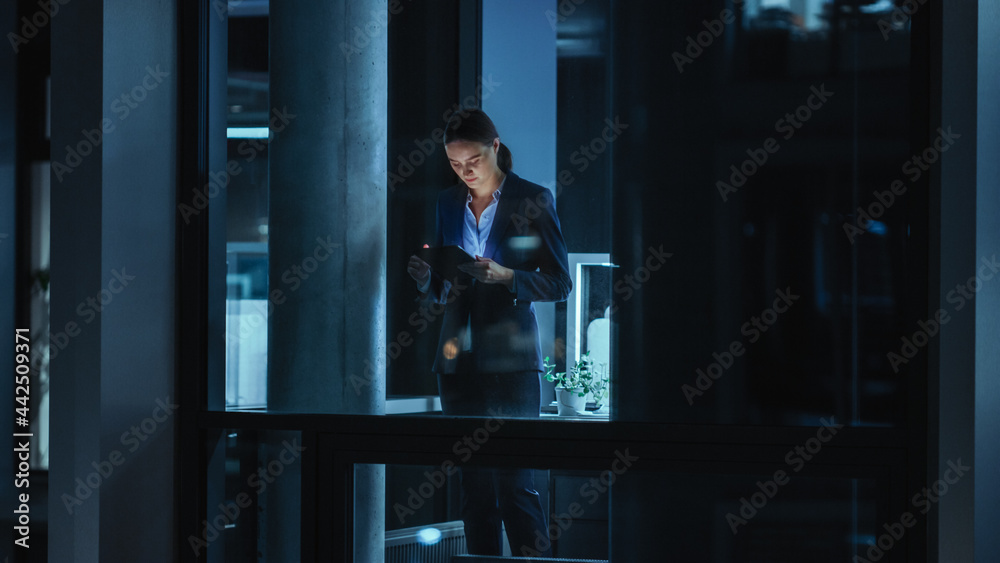 Poster Shot from Outside: Businesswoman Working on a Tablet Computer in the Office. Manager Checking Emails while Standing by the Window. Employee Planning Financial Tasks and Business Development.