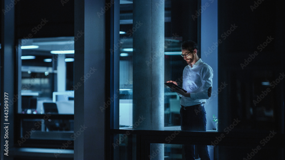 Poster Shot from Outside: Businessman Working on a Digital Tablet Computer in the Office. Manager Checking Emails while Standing by the Window. Employee Planning Financial Tasks and Business Development.