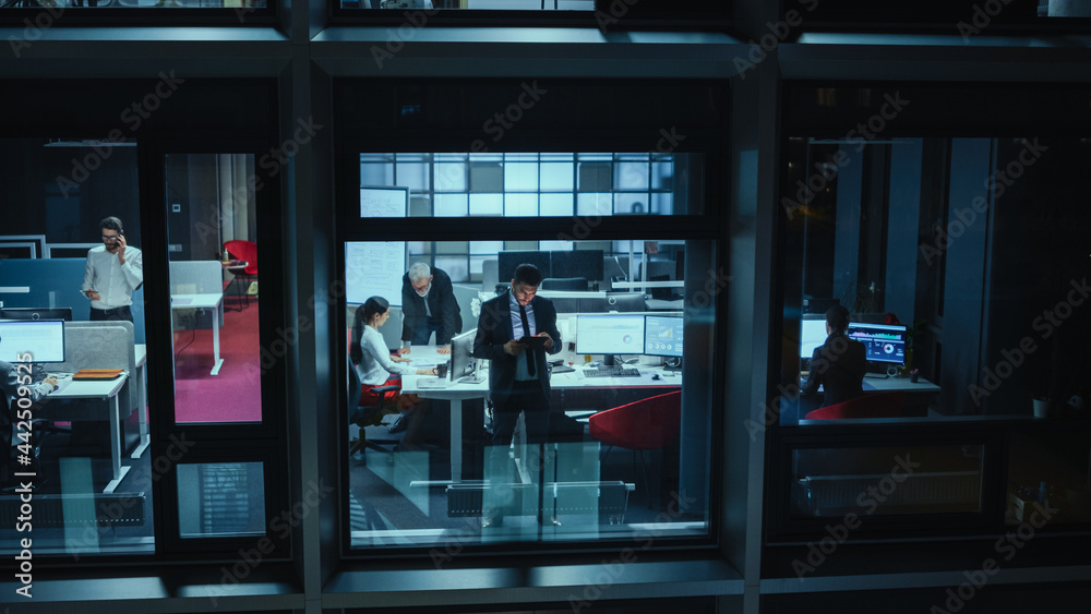 Poster Shot from Outside: Businessman Working on a Digital Tablet Computer in the Office. Manager Checking Emails while Standing by the Window. Employee Planning Financial Tasks and Business Development.