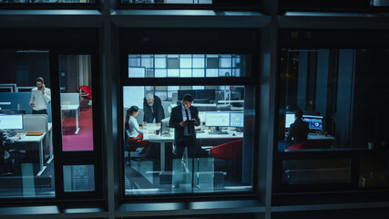 Shot from Outside: Businessman Working on a Digital Tablet Computer in the Office. Manager Checking Emails while Standing by the Window. Employee Planning Financial Tasks and Business Development.