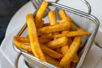 delicious french fries, sprinkled with spices in a metal dish