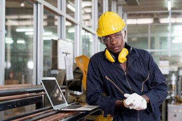 Technicians or engineers are inspecting machine operations using a laptop computer. Portrait of cheerful worker wearing protective posing looking at camera and enjoying work. - Powered by Adobe