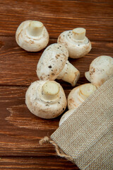 side view of fresh mushrooms scattered from sack on rustic wooden background