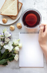 Top view of a blank notepad sheet and woman's hand in breakfast setting
