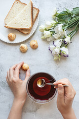 Top view of a woman's hands with a cup of tea, cookies, toasted bread and flowers