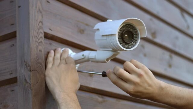 Technician installing wireless CCTV camera security system at house. Concept of surveillance and monitoring.