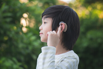 Asian child with hearing aid on nature background - Powered by Adobe