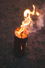 Burning log Swedish candle with fire for the warmth of camping in the forest
