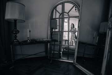 Young, slender girl reflected in an old mirror