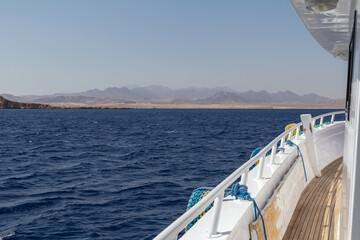 View from yacht while sailing on sea with mountains on background.