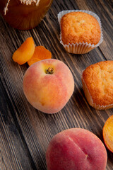 Naklejka na ściany i meble side view of fresh ripe peach with muffins dried apricots on rustic wooden background