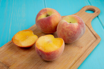 Naklejka na ściany i meble side view of fresh ripe peaches on a wooden cutting board on blue background