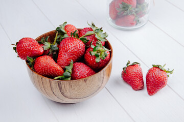 side view of fresh ripe strawberries in a wooden bowl on white background