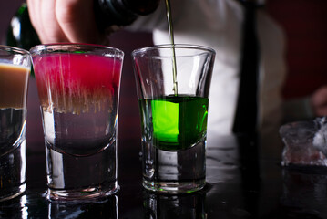 Barman preparing cocktail shots at the bar counter. Barman mixing drinks at the night club..