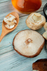 side view of fresh sliced mushrooms in a wooden spoon bottle of olive oil on rustic wooden background