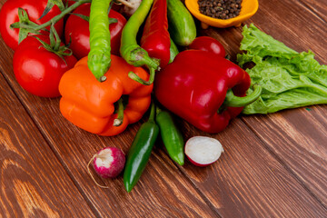 side view of fresh vegetables colorful bell peppers cucumbers ripe tomatoes green chili peppers radish and black peppercorns on wooden rustic background