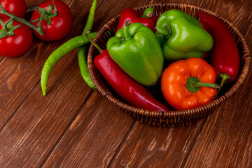 side view of fresh vegetables colorful bell peppers red chili peppers in a wicker basket on wooden rustic background