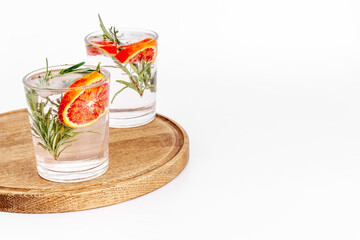 Red orange lemonade in glasses with ice and rosemary