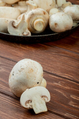 side view of fresh white mushrooms on a tray on rustic wooden background