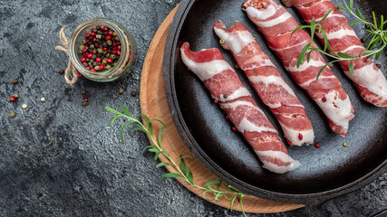 minced meat wrapped in bacon on cast iron plate. chevapchichi or Kofta kebab. raw sausages of...