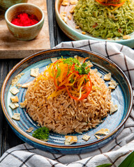 side view of fried japanese rice with vegetables in soy sauce on a plate on wooden background