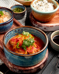 side view of fried shrimps with vegetables and spicy sauce in a bowl on rustic background