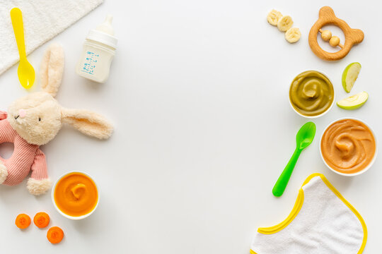 Bowls of various baby food and bottle of milk, top view