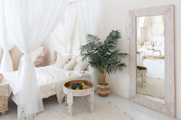 daylight through a huge panoramic window illuminates the cozy oriental interior of the room in beige colors with wicker furniture and authentic elements