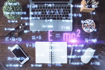 Physics and math theme hologram with formula drawings over computer on the desktop background. Top view. Multi exposure. Concept of education.