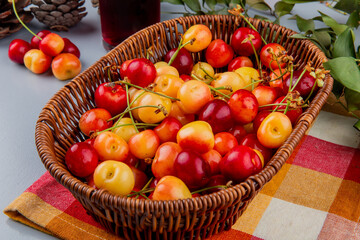 side view of ripe rainier cherries in a wicker basket on plaid napkin on the table