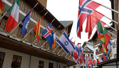 Obraz premium Many national flags of different states hang and blowing on building. Worldwide. International Flags are flying on building. Israeli, Icelandic, Norwegian, Spanish, American, Greek Flags.