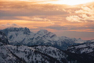 Dramatic colors effect of winter panorama of Pale di San Martino Peaks at sunset with sunlit clouds. Fiorentina Valley, Dolomites, Italy