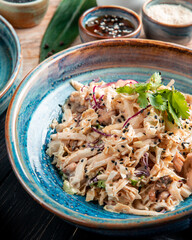 side view of salad with chopped cabbage chicken and black seeds in a plate on wooden background