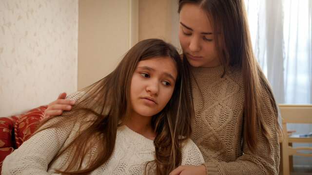 Teenage Girl Consoling And Stroking Her Upset Girl Friend Talking About Problems In Relationships. Friends Support And Teenager Depression